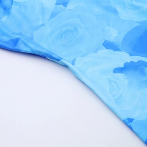 Dettaglio ravvicinato della stampa floreale con rose blu su morbido tessuto a maglia del vestito