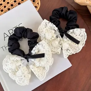 Elegant set of two black scrunchies featuring large white lace bows with floral embroidery