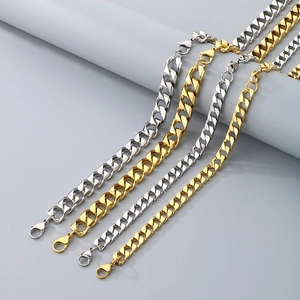 Polished gold and silver Cuban link chains with lobster clasps hanging on a studio prop