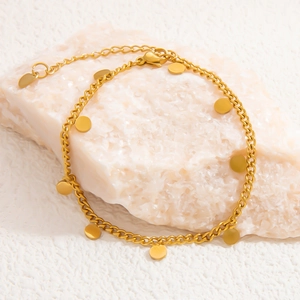Close-up of 18k gold-plated stainless steel chain with round charms on a white stone