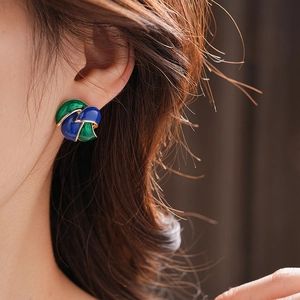 Detail of vintage French style enamel earrings with blue and green gold leaf patterns