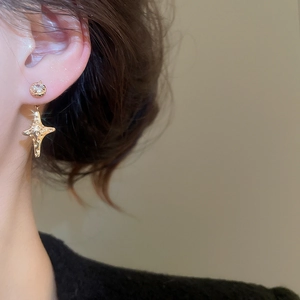 Close-up of gold plated star earring with zircon stone inlay worn by a female model
