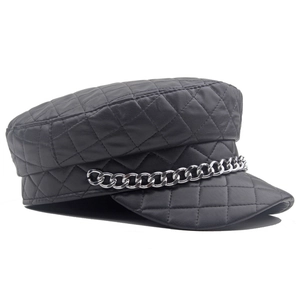 Close-up of quilted black leather baker boy cap with bold silver metal chain detail