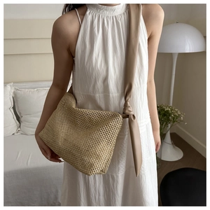 Detail of woven straw tote bag with wide tied synthetic leather shoulder strap