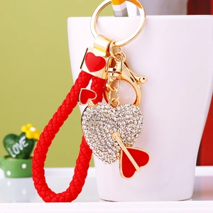 Detail of crystal heart and arrow keychain with red woven strap and gold metal clasp