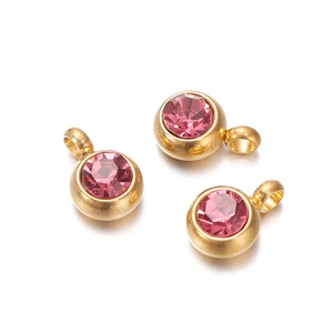Macro detail of three gold-plated round pendants with pink faceted zircon stones