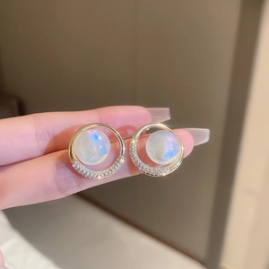 Detailed view of gold circle earrings with iridescent pearls and cubic zirconia stones