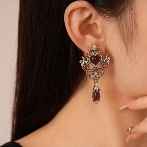 Vintage gold earrings with purple heart gems and water drop pendants on model