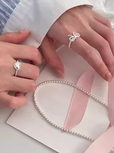 Detail of S925 silver lace heart ring and bow ring with pearl necklace set on model