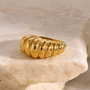 Bague croissant en acier inoxydable doré 18 carats exposée sur un socle en pierre texturée