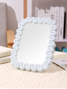 Close-up of light blue wavy frame desktop makeup mirror in a cozy home setting