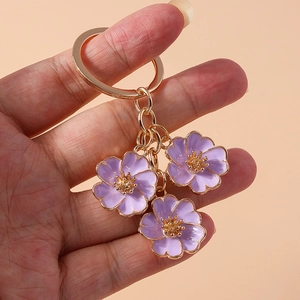 Detailed macro of purple flower keychain with gold metal chain and enamel flower charms