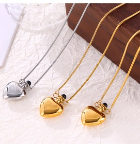 Close-up of heart-shaped perfume bottle pendants on a wooden box with sleek snake chains