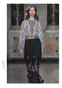 Detail of green snakeskin pattern belt with metallic buckle on a grey lace blouse