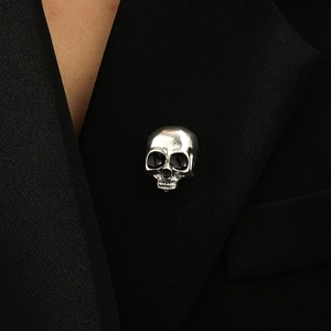 Macro detail of a vintage silver skull brooch pinned to a black suit lapel