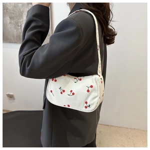 White corduroy cherry print tote bag shown on model shoulder for size and fit