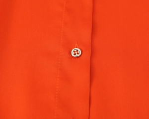 Detailed close-up of orange satin shirt collar with a metallic silver button