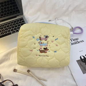 Close-up of quilted cream pouch with dachshund embroidery and 'Have a nice day' text