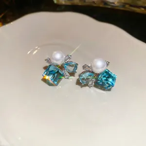 Square blue crystal earrings with drop gem and pearl on elegant ceramic tray