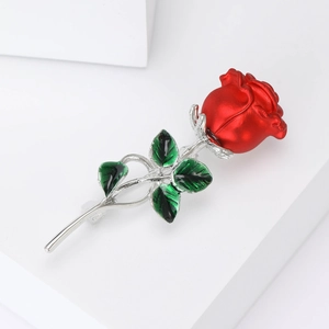 Detail view of a rose brooch with red petals, green leaves and silver metallic stem