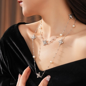 Gros plan d'un collier de perles argenté à double épaisseur avec breloques fleurs