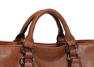 Detail of caramel brown tote bag handle with lychee texture leather and metal rings