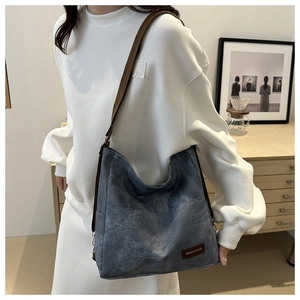 Detail of blue canvas tote bag with brown adjustable strap and fashion logo tag