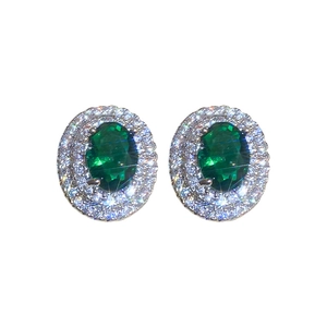Elegant silver stud earrings with oval emerald stones and double zircon halo on white background