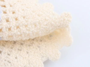 Close-up of cream-white crochet fabric showing intricate knit texture and soft yarn detail