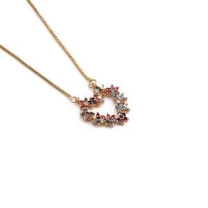 Macro detail of gold-plated heart pendant with colorful inlaid zircon gemstones