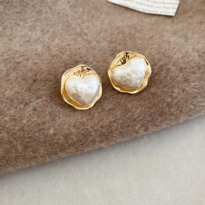 Dettaglio di orecchini a lobo a cuore placcati oro 16K con perla bianca barocca