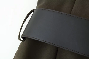 Close-up of olive woven fabric and dark brown leather belt with precise stitching detail