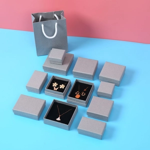 Detailed overhead view of various grey textured jewelry gift boxes with matching gift bags