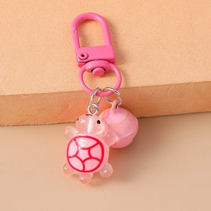 Close-up of pink resin turtle keychain with matching bell and metallic lobster clasp