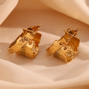 Close-up of hammered 18K gold plated earrings with irregular textured finish on beige fabric