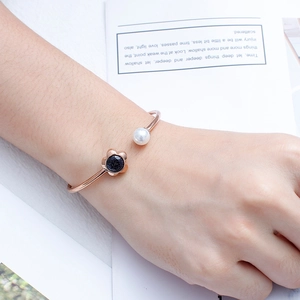 Detail of rose gold open cuff bracelet with pearl and blue flower on woman's wrist