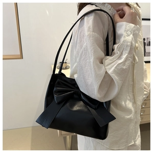 Detail of minimalist black PU shoulder bag featuring a large decorative leather bow design
