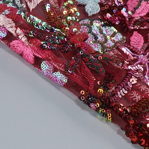 Detail of burgundy mesh fabric with colorful sequins and floral embroidery for dress