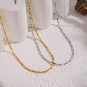 Minimalist gold and silver geometric link chains on white textured background