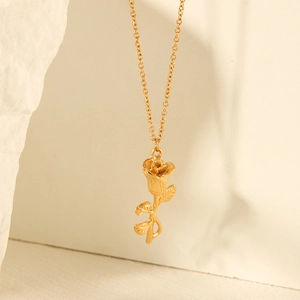 Elegant gold rose pendant necklace with detailed petals on minimalist white stone background