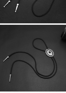 Macro detail of ornate silver-tone bolo tie slide and textured tips on woven leather cord