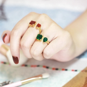 Detail of gold-plated open rings featuring emerald and ruby colored zircon stones