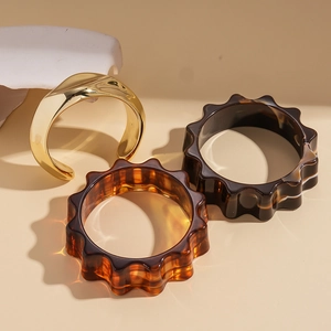 Three-piece set with golden metal wave bangle and amber resin flower gear bracelets
