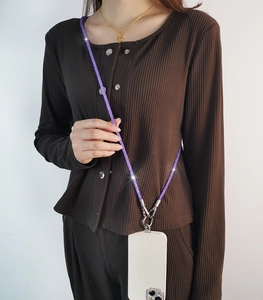Detail view of purple rhinestone crossbody phone lanyard worn on white mobile case