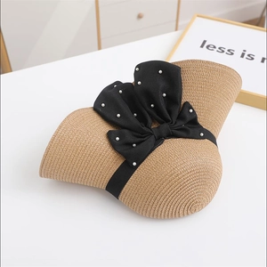 Detail of woven straw sun hat with large black satin bow and pearl embellishments