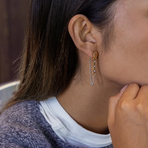 Vue détaillée de boucles d'oreilles à pompons bicolores or et argent sur un mannequin