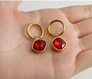 Nahaufnahme der 18K vergoldeten Edelstahl-Ohrringe mit roten Zirkonia in der Hand