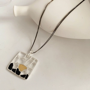 Détail du pendentif géométrique mat avec motif grille sur une chaîne à double rang
