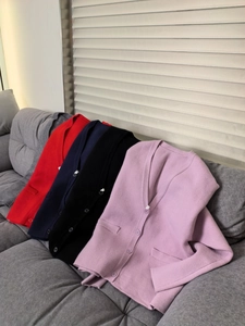Detail of V-neck knit cardigans in red, navy, pink, and black colors on a sofa