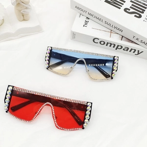 Détail de lunettes de soleil oversize à strass avec verres rouges et dégradés bleus
